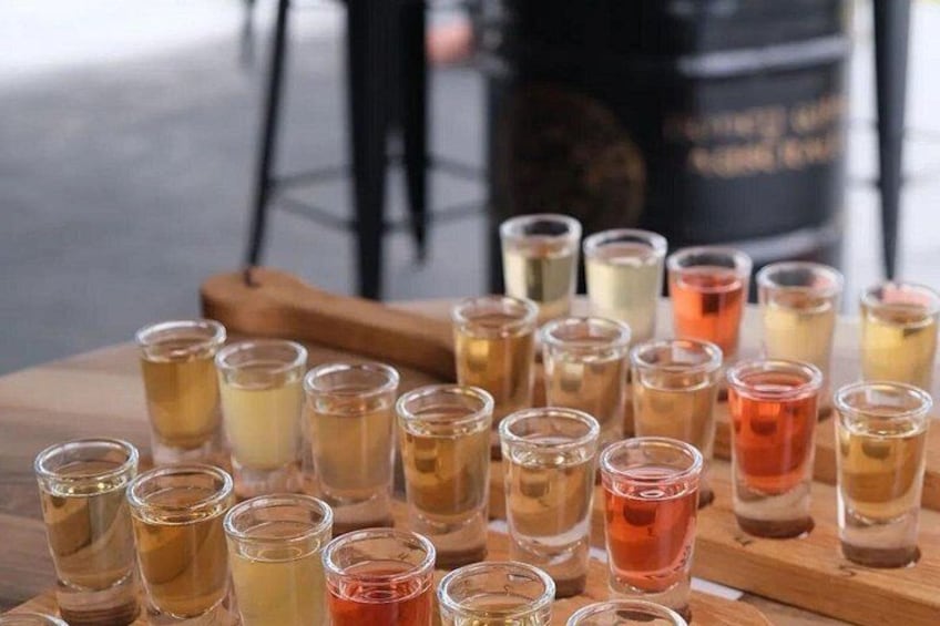 A wooden table with shot glasses filled with various colored liquids. 1