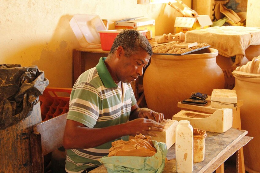 A man working with dough on a wooden table in a rustic kitchen setting. 5