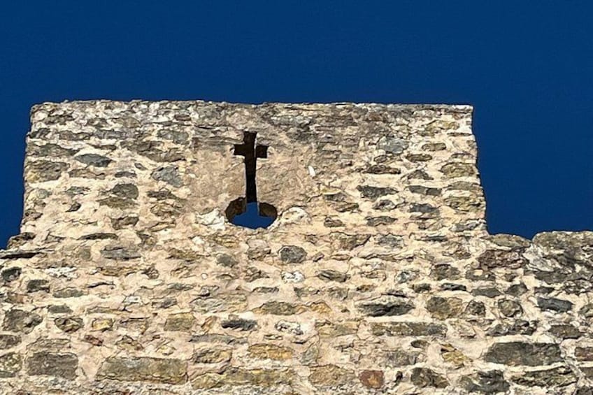 Un mur de pierre dans lequel est incrustée une croix. 2