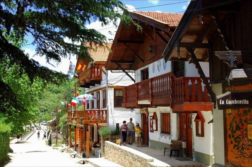 A traditional wooden building with balconies, a stone wall, and a sign reading 'La Cumbreclita'. 4
