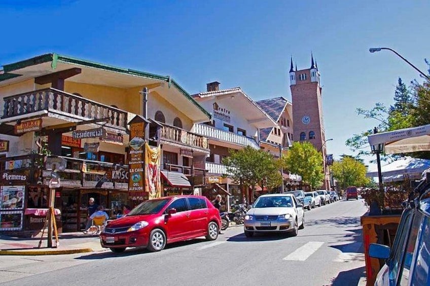 A street with cars, buildings, and a clock tower. 2