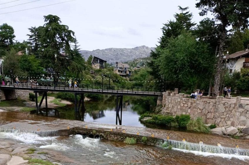 A stone bridge over a river, surrounded by trees and buildings. 1