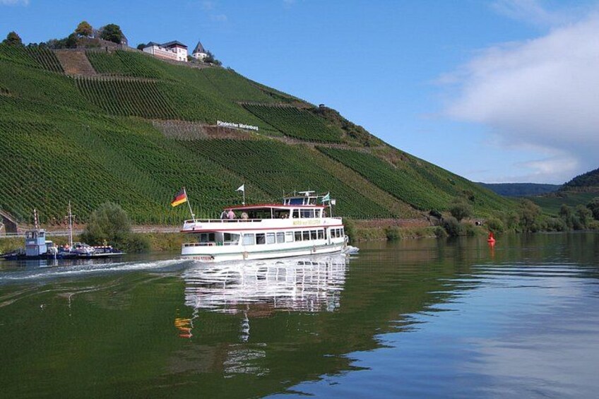 Een rivier met een bootje, groene heuvels en een kasteel op de achtergrond. 3