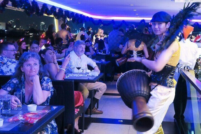 A person playing a drum in a crowded indoor setting. 2