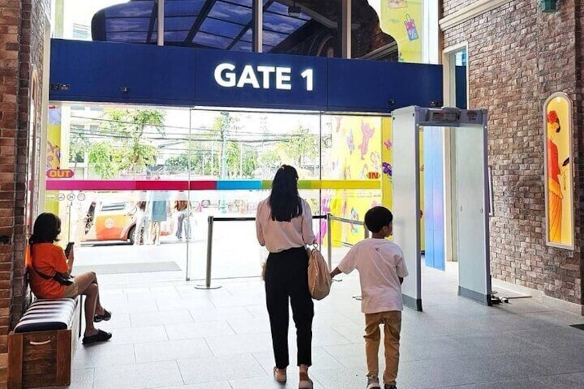 A woman and a child walking towards a gate labeled 'GATE 1' in a public building. 4