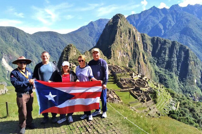 Un grupo de personas sosteniendo una bandera frente a Machu Picchu. 1