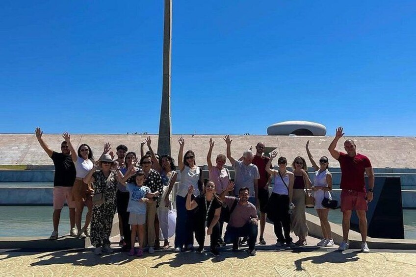 Un grupo de personas posando frente a un monumento con un cielo azul despejado al fondo. 5