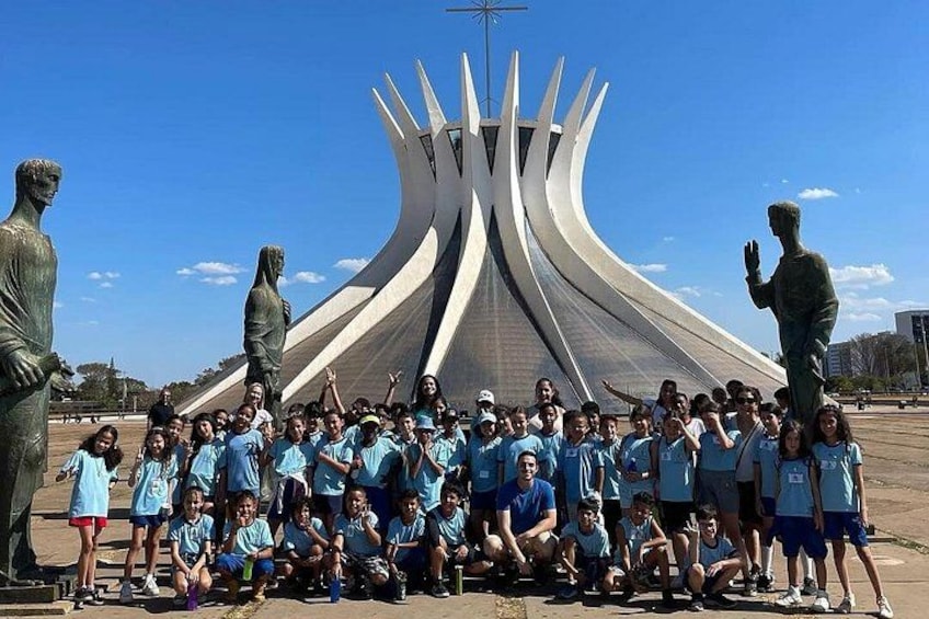 A group of people posing in front of a modern sculpture with a unique, curved design. 3