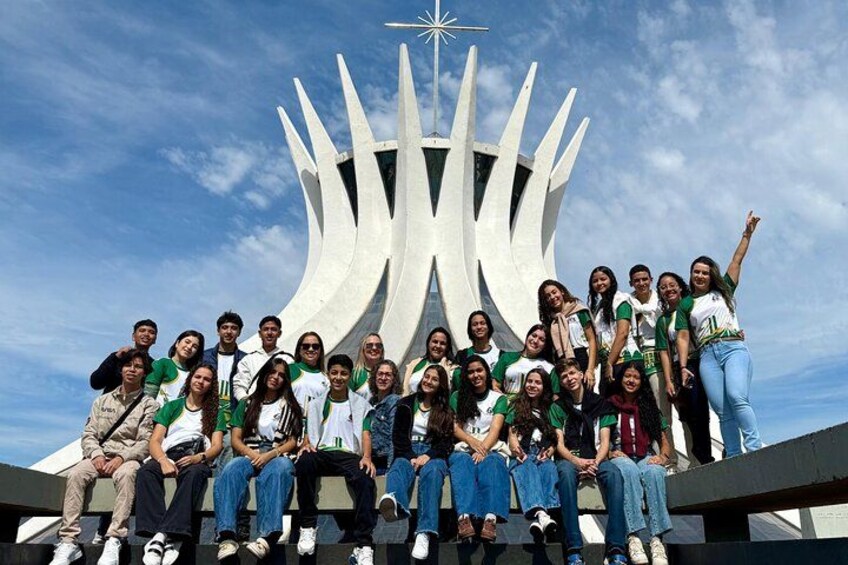 Un grupo de personas posando frente a una escultura moderna con una estrella en la parte superior. 1