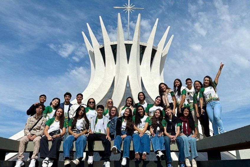 A group of people posing in front of a modern sculpture with a star on top. 1