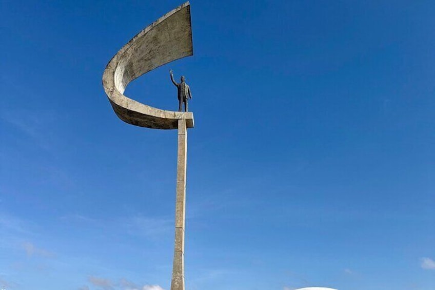 A large, curved concrete structure with a figure standing on top. 5
