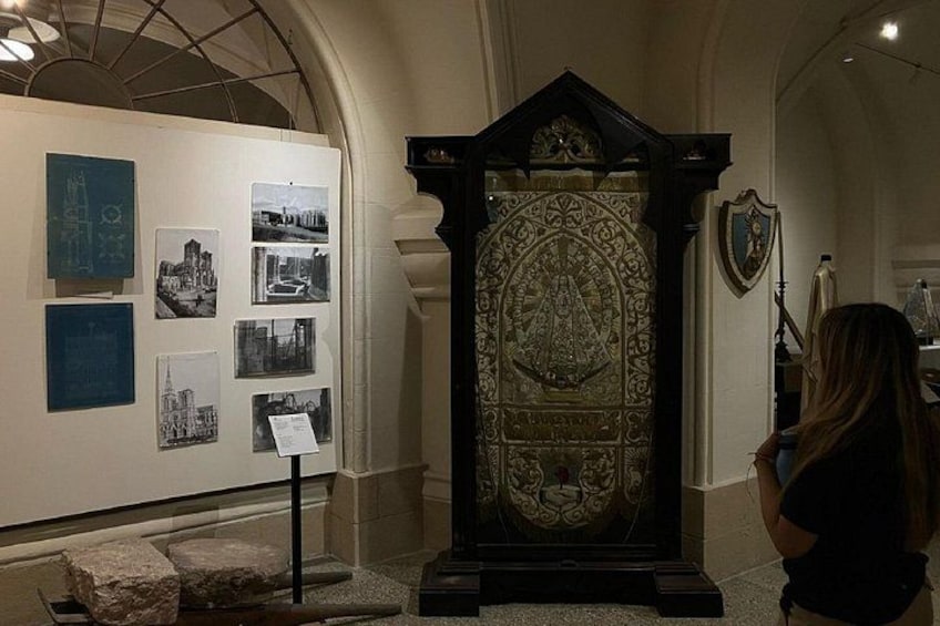 An ornate religious artifact on display, surrounded by photographs and informational placards. 3