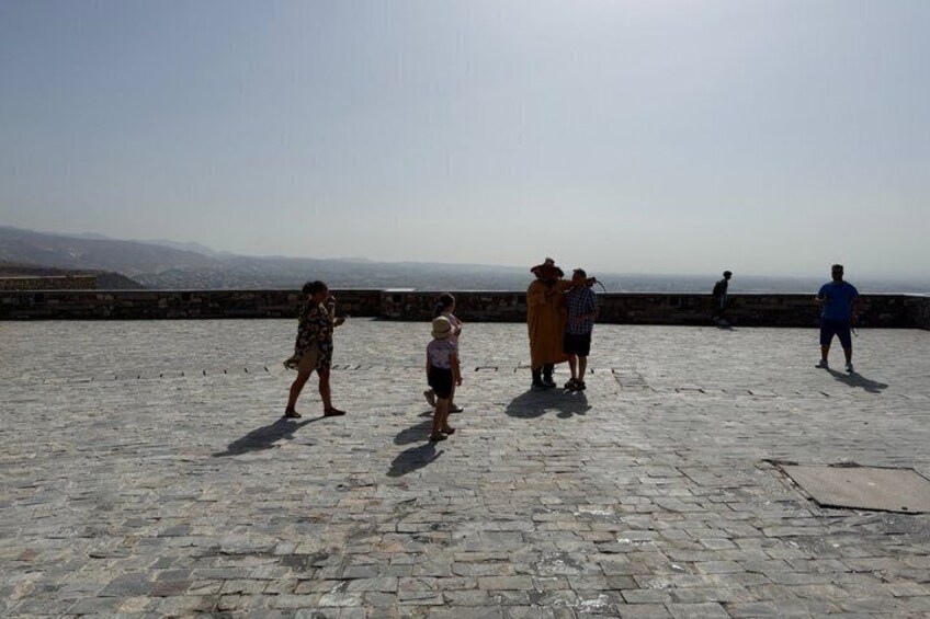 Eine Gruppe von Menschen auf einer steinbelagten Terrasse mit Blick auf eine Stadtlandschaft. 2