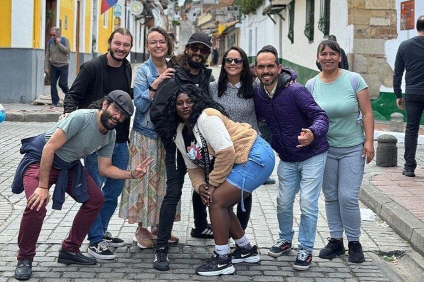 Un grupo de personas posando en una calle adoquinada con edificios al fondo. 2