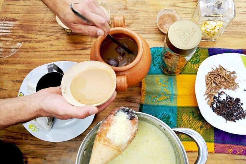 Una mesa de madera con una olla de barro, un plato de sopa, una taza de café y un plato con especias. 5