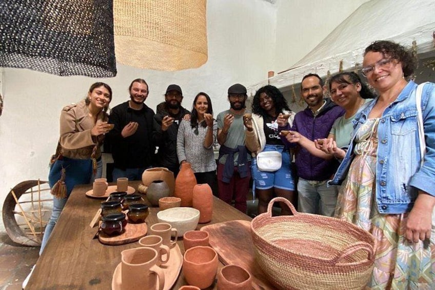 Un grupo de personas alrededor de una mesa con cerámica y cestas tejidas. 3