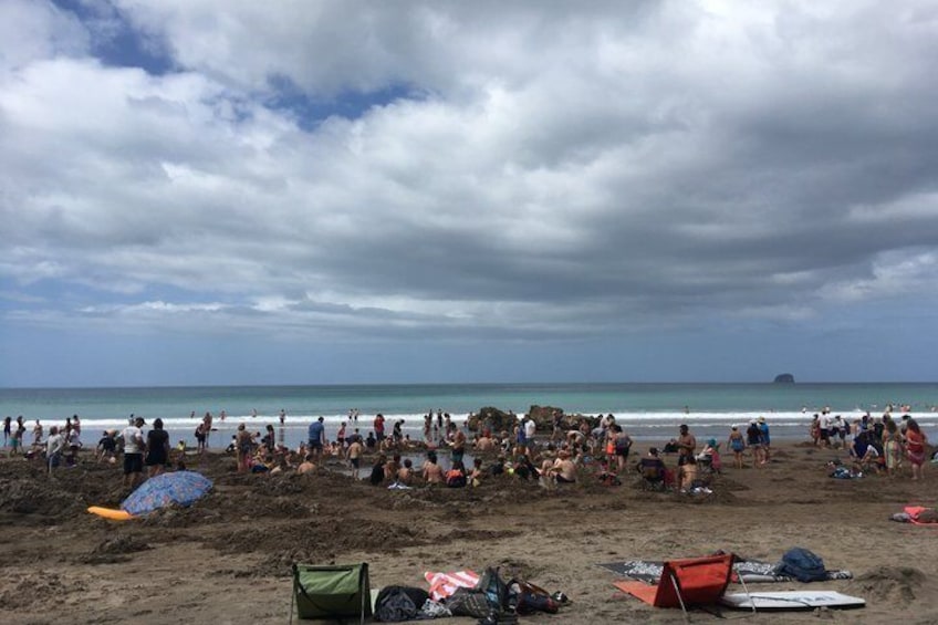 A crowded beach with people, tents, and a distant island. 3
