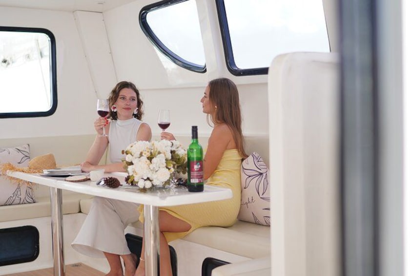 Two people sitting at a table on a boat with a bottle of wine and a bouquet of flowers. 3