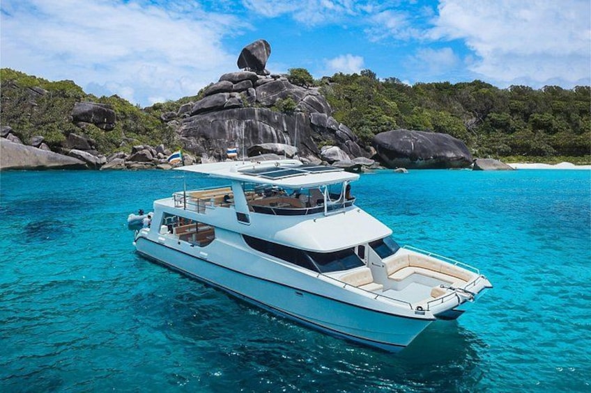 A white yacht on turquoise waters with a rocky island in the background. 1