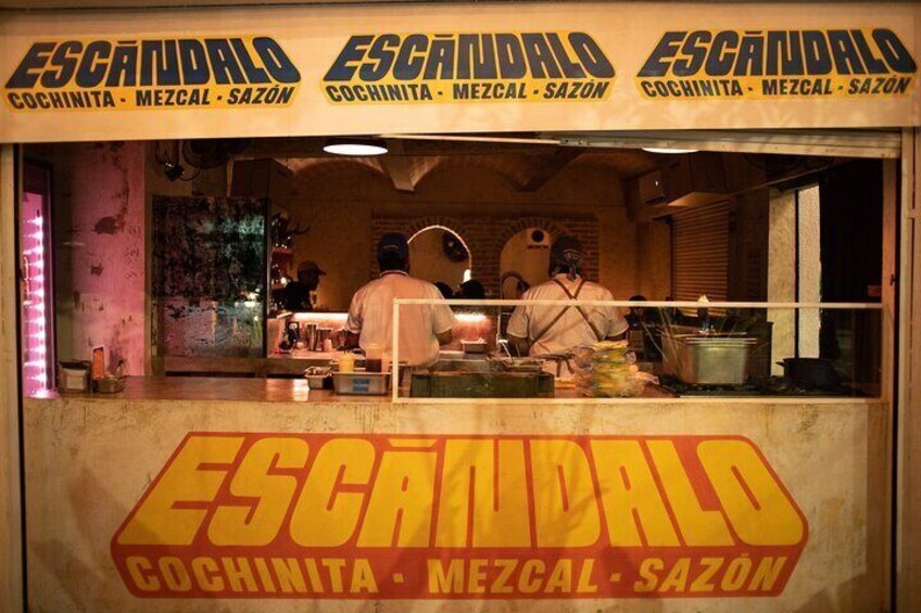 En matstånd som heter Escandalo, med en skylt som visar Cochinitas, Mezcal och Sazon. 2