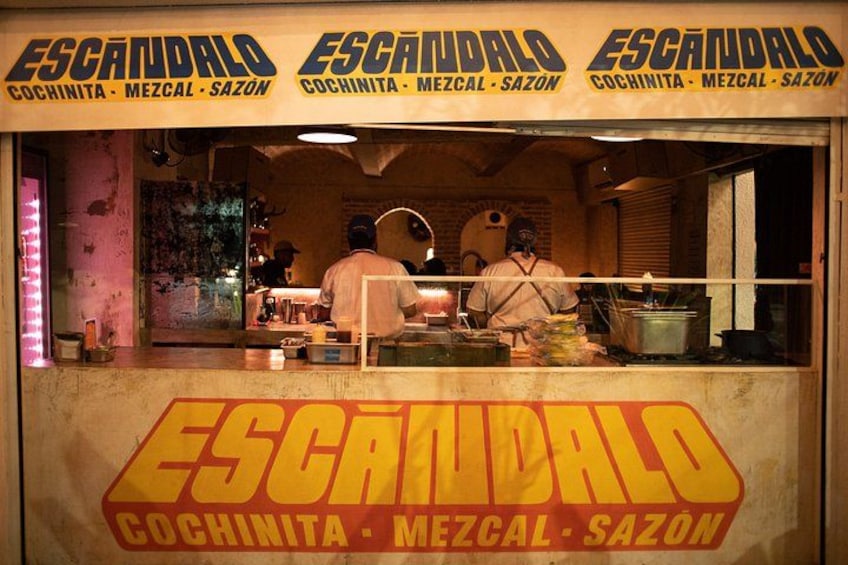 A food stall named Escandalo with a signboard and two people working behind the counter. 2