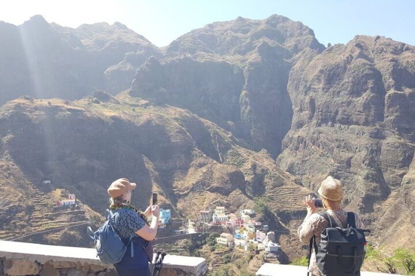 Two people taking photographs of a mountainous landscape with terraced fields below. 4