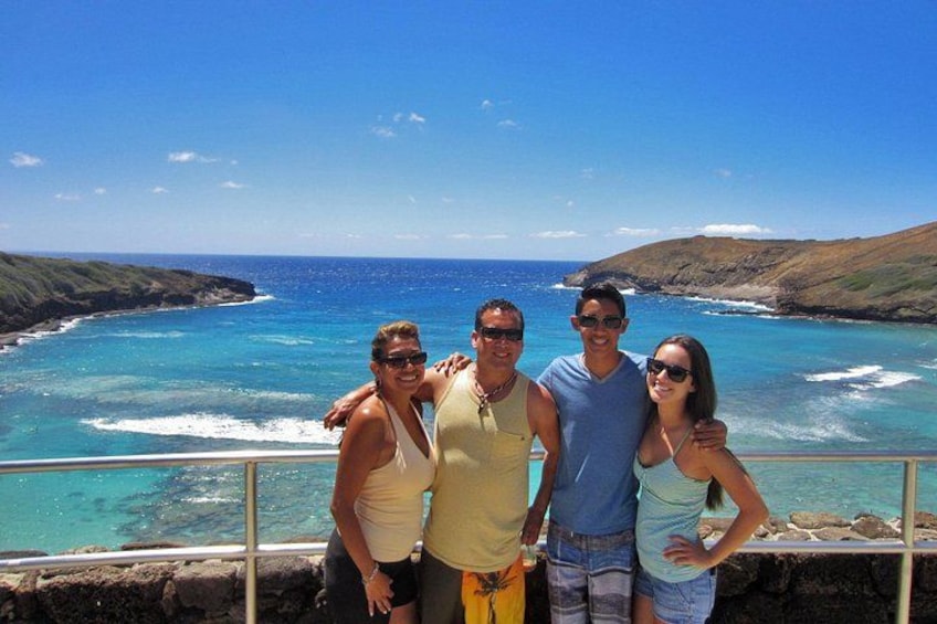 A group of people standing by a coastal cliff overlooking a turquoise sea with waves crashing against the shore. 5