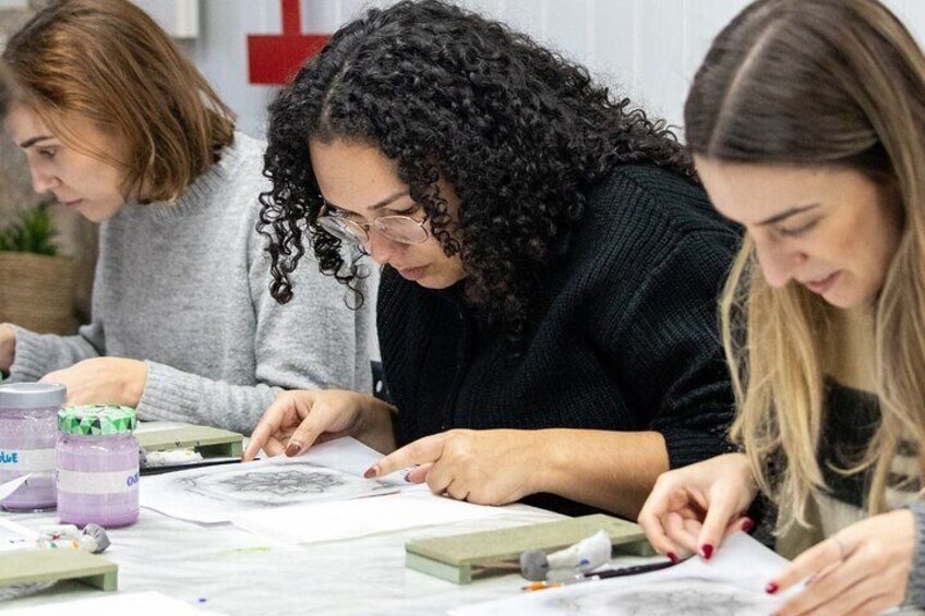 Three people engaged in a drawing activity at a table with art supplies. 1
