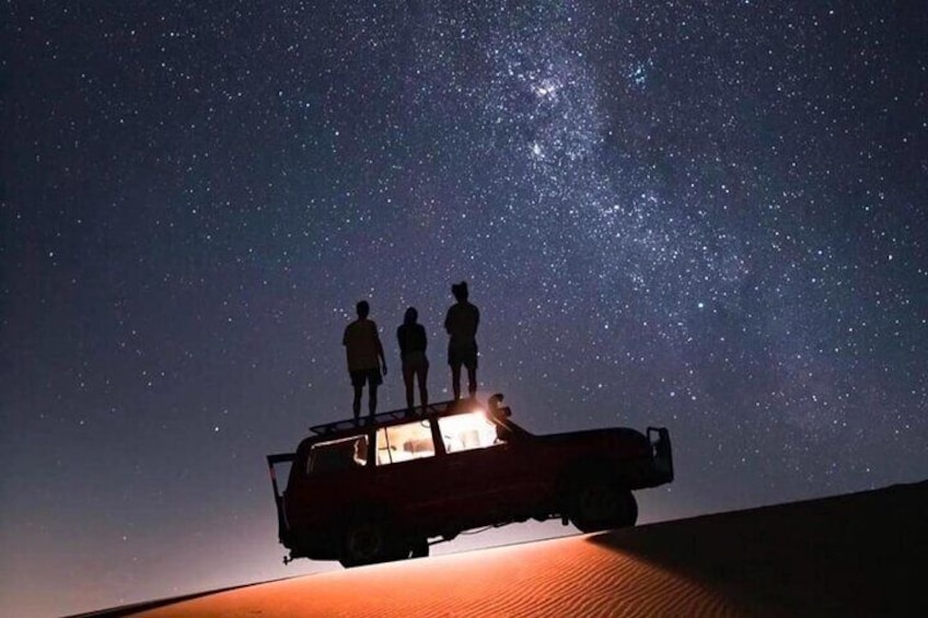 Un veicolo con tre persone in piedi sul tetto sotto un cielo stellato. 5