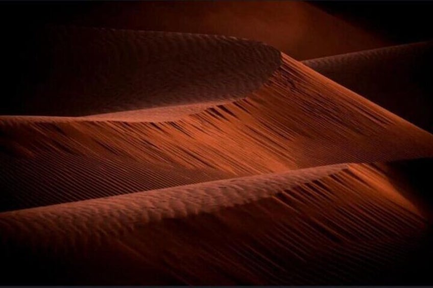Un primo piano di dune sabbiose con ondulazioni e ombre. 4