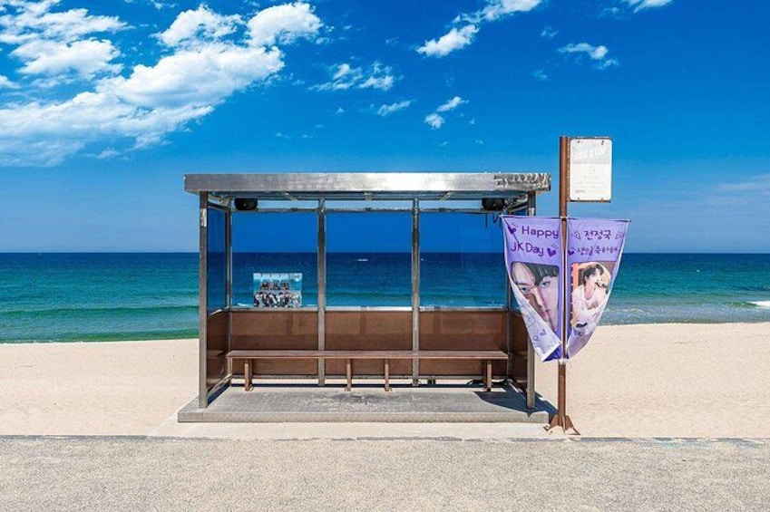 A beach kiosk with a bench, a poster, and a signboard. 1