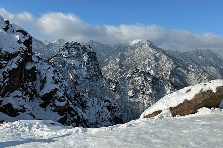 A snow-covered mountain landscape with rocky outcrops and a clear sky. 5