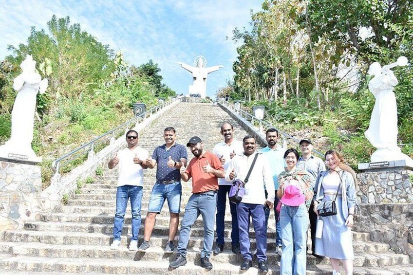 A group of people standing on stone steps with a statue at the top. 3