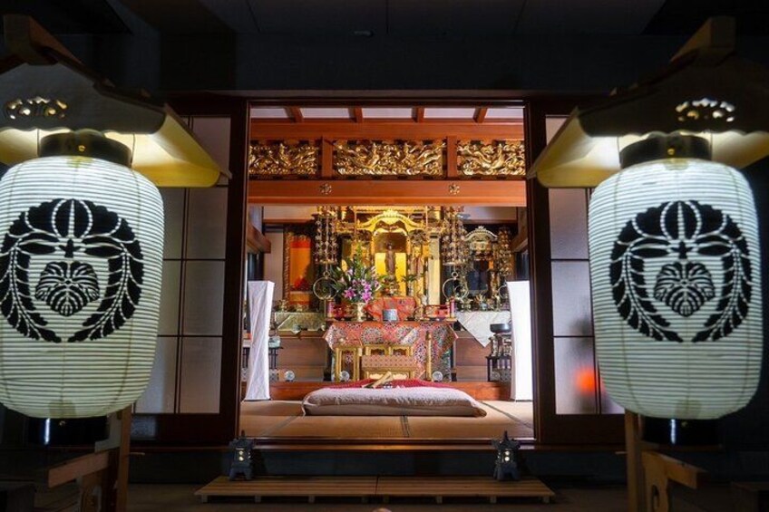 A traditional Japanese interior with a tatami mat room, a wooden altar, and two illuminated lanterns. 2
