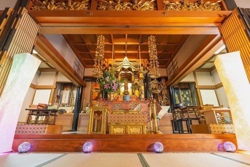 A traditional temple interior with ornate golden decorations, a central altar, and a tiled floor. 5