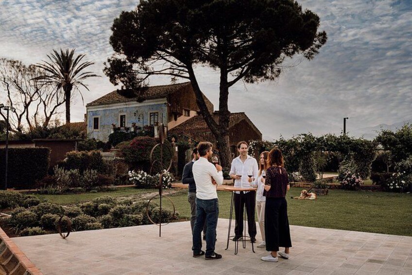 A group of people standing outdoors in a garden with a house in the background. 3