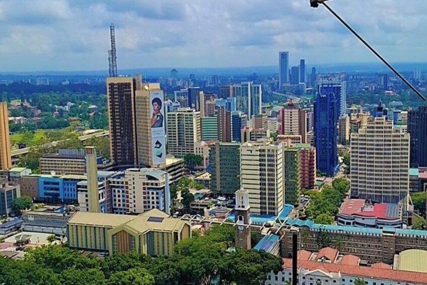 A cityscape with a mix of modern and older buildings, a prominent tower, and a clear sky. 1