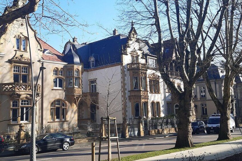 Eine Straße mit historischen Gebäuden, einem geparkten Auto und kahl stehenden Bäumen. 3
