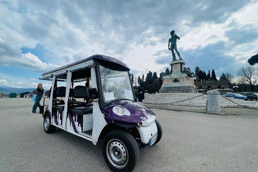 A small vehicle parked near a statue. 2