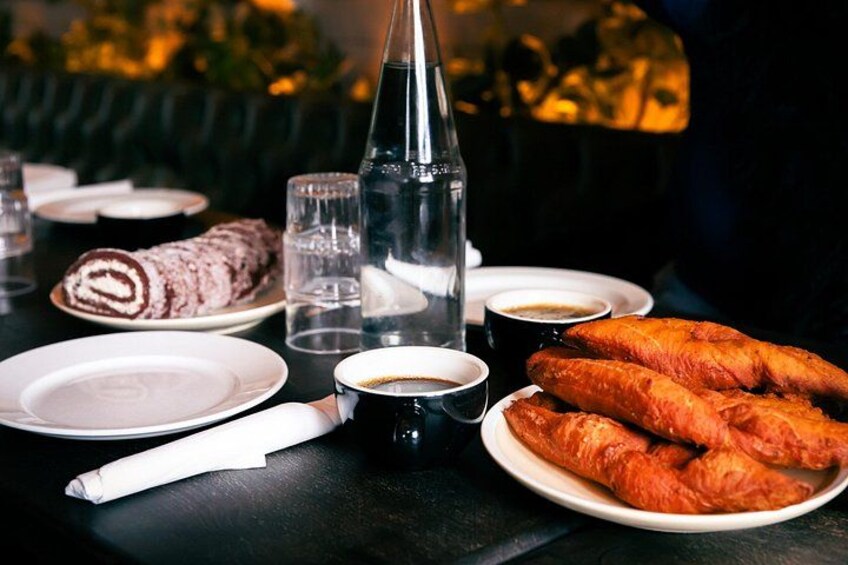 A table with pastries, a bottle, glasses, and cups. 3