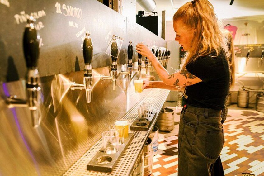 A person operating a beer tap machine in a bar setting. 3