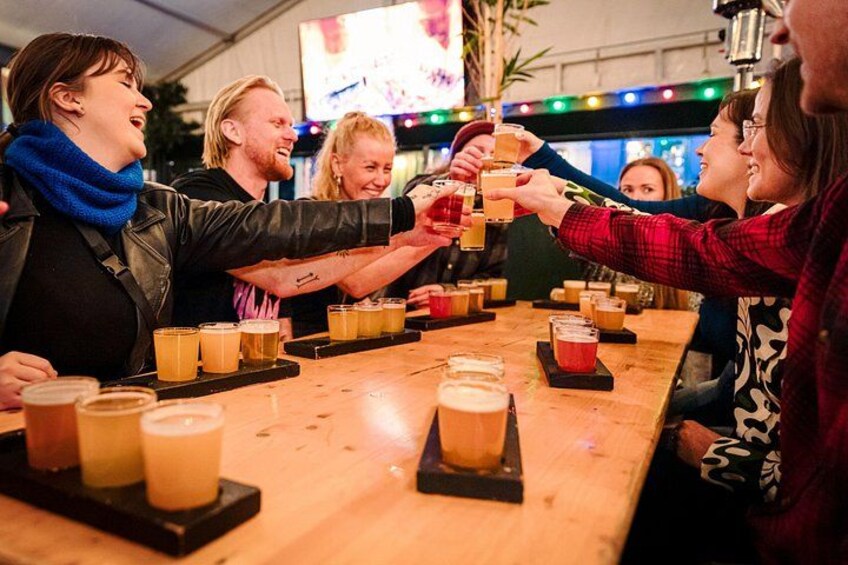 A group of people toasting with beer glasses at a bar. 5