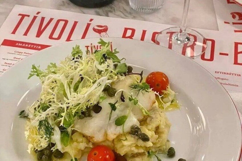 A plate of food with a white plate, green salad, cherry tomatoes, and a glass of water. 4