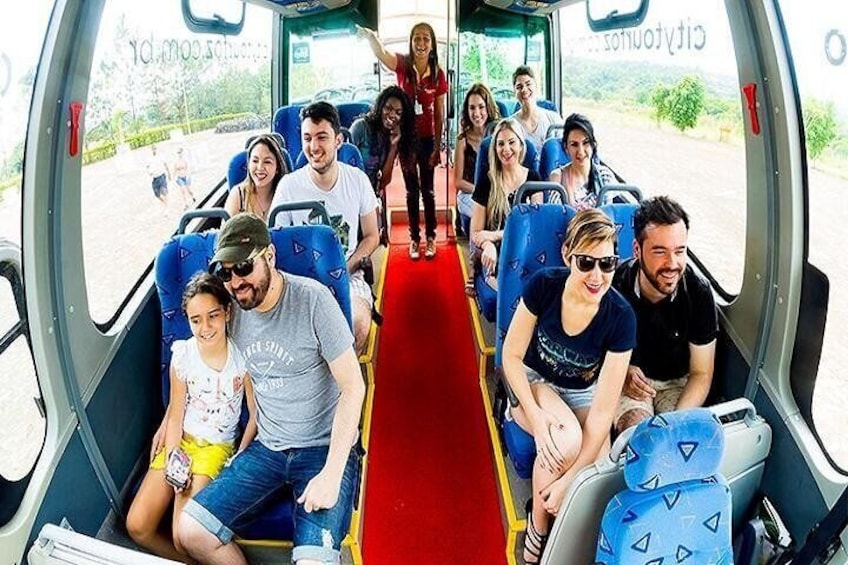 En grupp människor i en buss med blå säten och en röd mittengång. 1