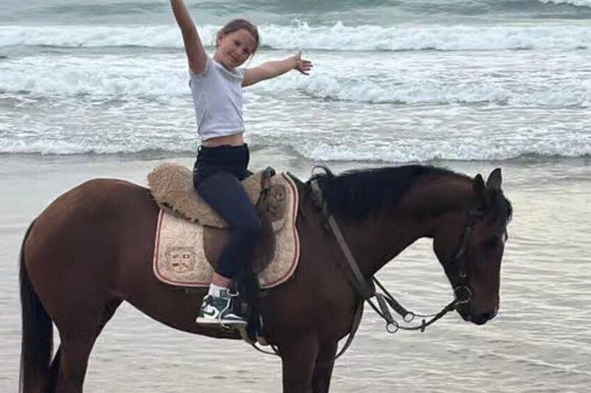 A person riding a horse on a beach with waves in the background. 4