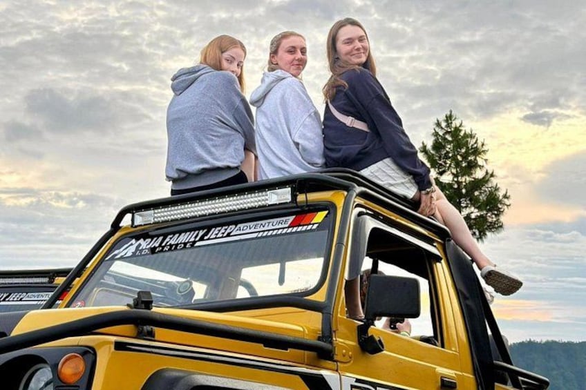 A yellow off-road vehicle with three people standing on top. 3