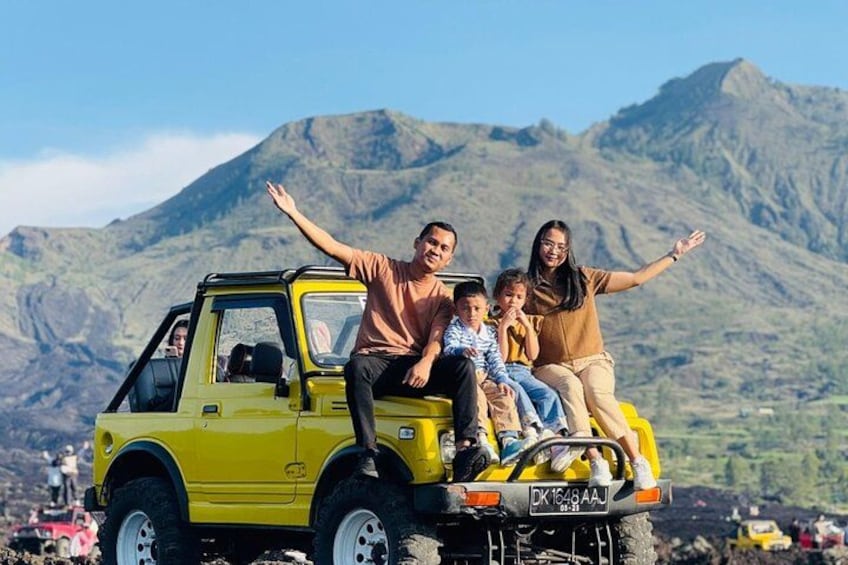 A yellow vehicle with people on top, a mountainous landscape, and a clear sky. 2