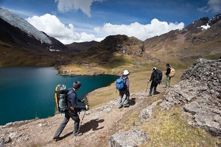 Un groupe de randonneurs sur un sentier rocailleux, avec un lac en arrière-plan. 1