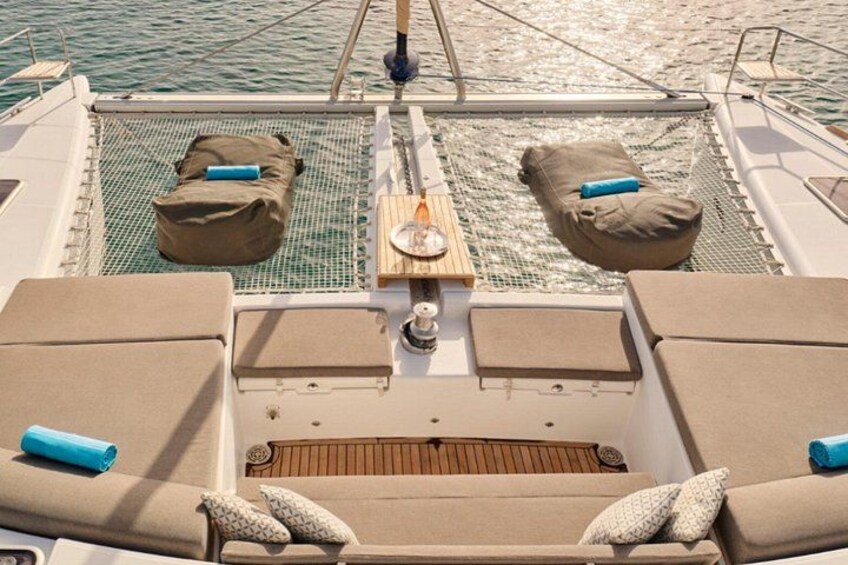 A boat deck with two cushioned seating areas, a small table, and a netted area. 1