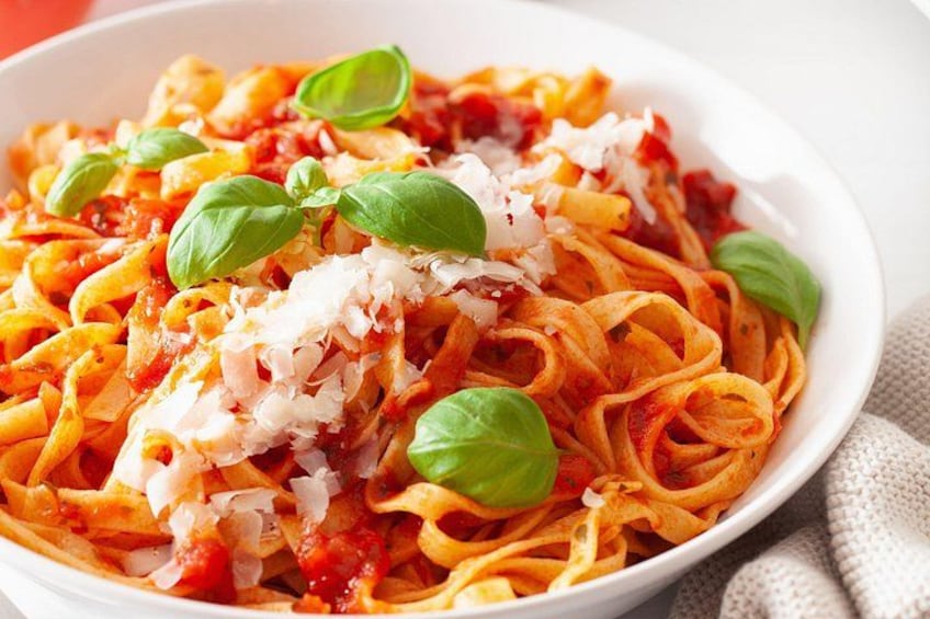 Un plat de pâtes à la sauce tomate, garni de feuilles de basilic et de fromage râpé. 3